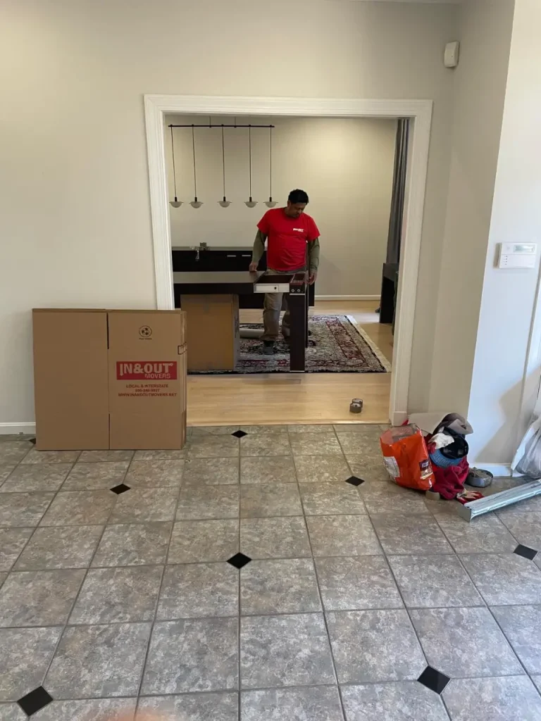 Mover assembling furniture among boxes inside a home during Moving Day setup.