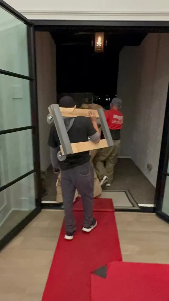 Professional movers carrying furniture into a home on Moving Day using protective equipment.