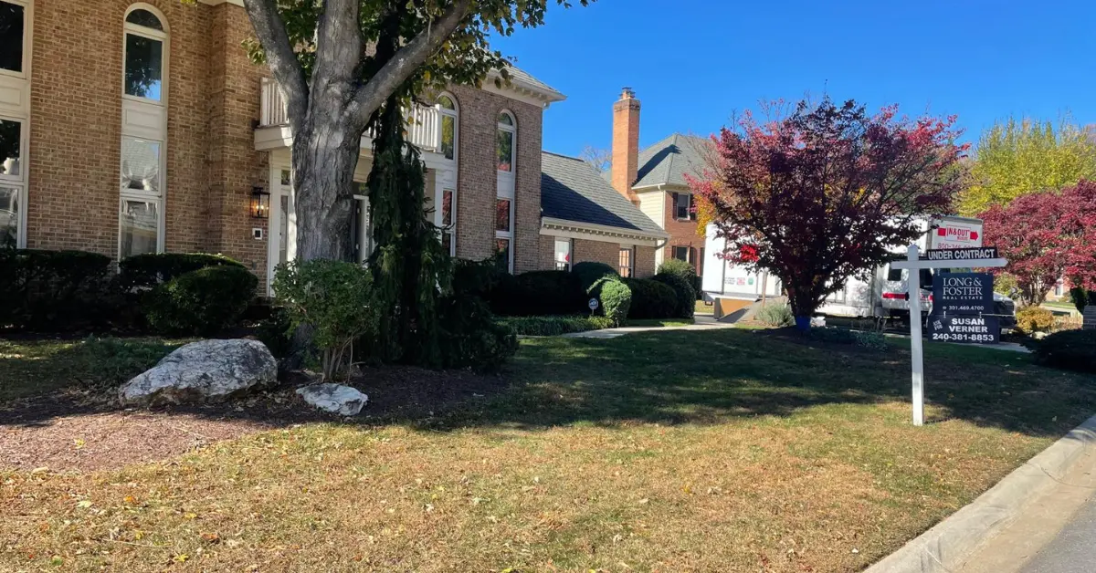 Brick suburban home with real estate sign and front lawn, representing families moving to Washington DC neighborhoods.
