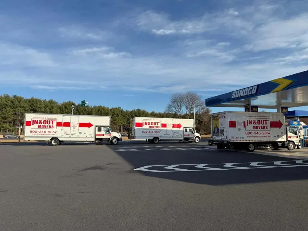 Three In & Out Movers trucks parked at a Sunoco station during transit for small international moves.