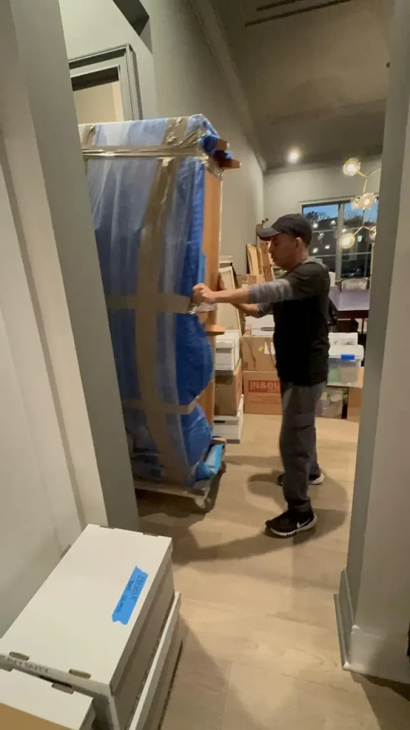 Professional mover wrapping furniture inside a home to protect belongings during moving with children.