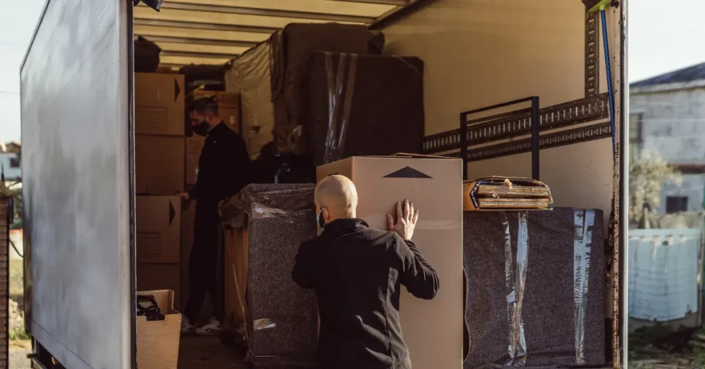 Workers loading packed boxes and furniture onto a moving truck, specializing in restaurant equipment movers.